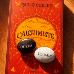 Pierres Ourim et Toumim gravées posées sur le livre L'Alchimiste de Paulo Coelho.