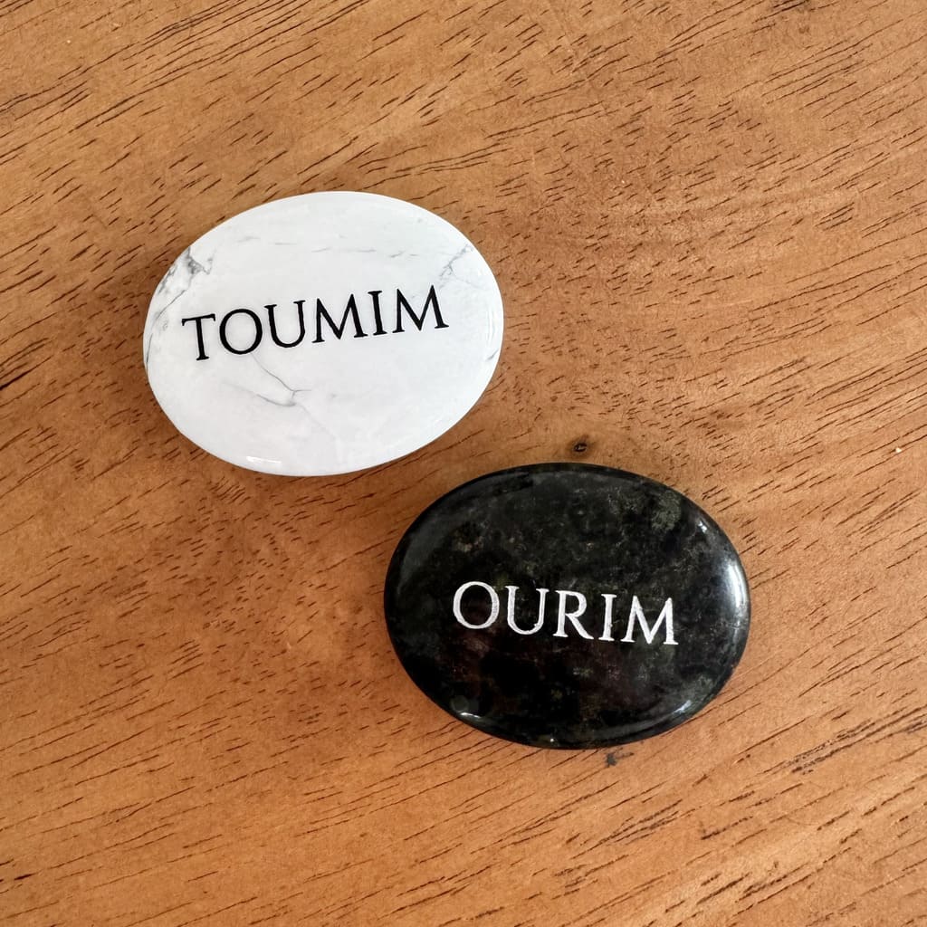 Pierres Ourim et Toumim gravées posées sur un fond en bois.